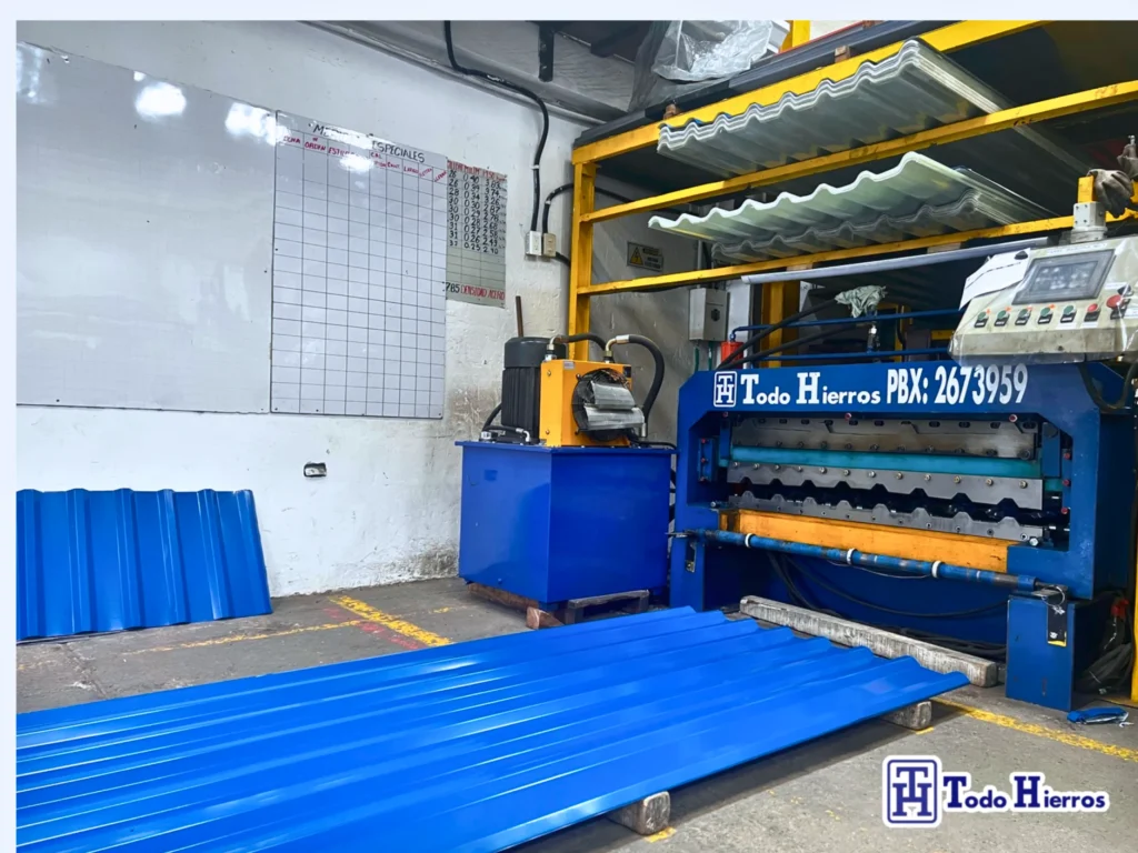 Línea de producción en la planta de Todo Hierros, con una máquina formadora y láminas para techo de color azul.